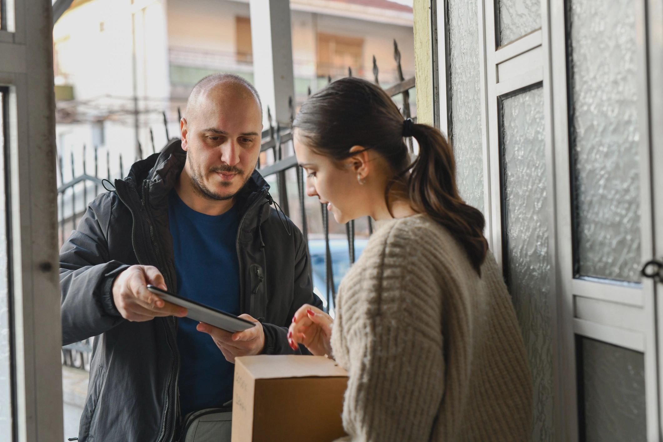 Salesperson at a doorway completing paperwork on a tablet